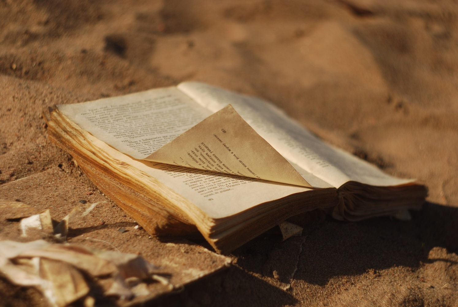 old open book laying in desert sand